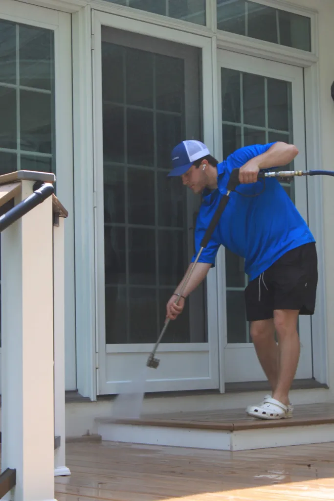 AllPro technician cleaning the glass doors of a back porch under a deck