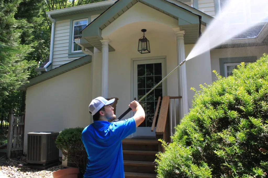 AllPro technician soft washing the front entry and portico of a two-story home