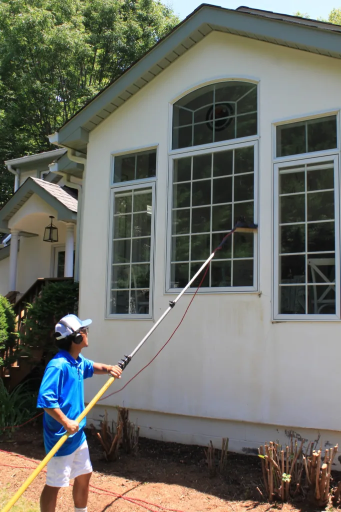 AllPro technician cleaning large arched windows with a water-fed pole