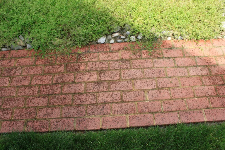 Weathered red brick retaining wall below a grassy slope
