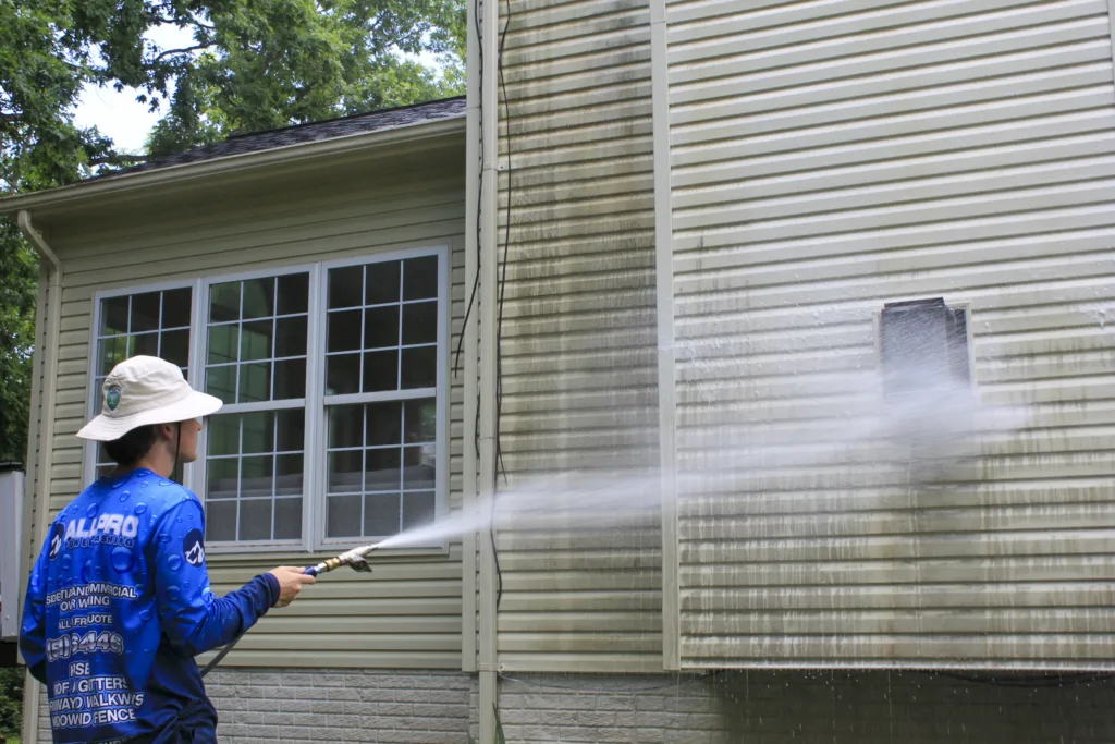 AllPro technician soft washing mildew off tan vinyl siding