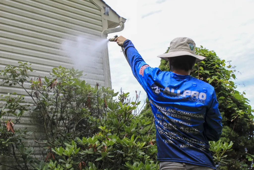 AllPro technician soft washing the vinyl siding of a home