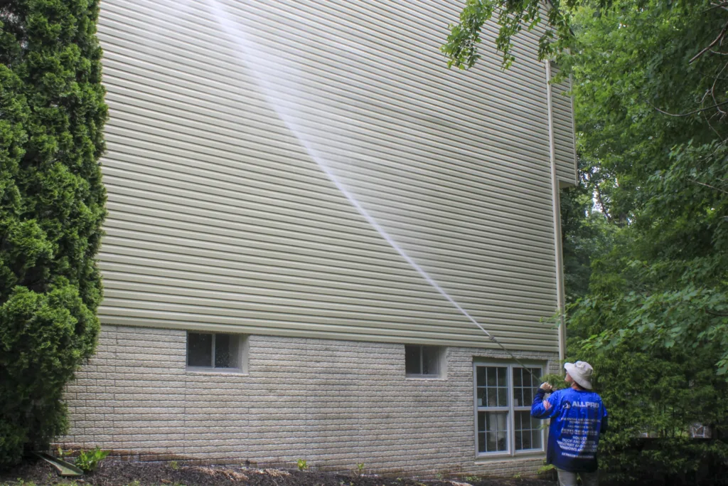 AllPro technician washing a tall wall of vinyl siding