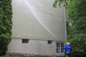 AllPro technician washing a tall wall of vinyl siding