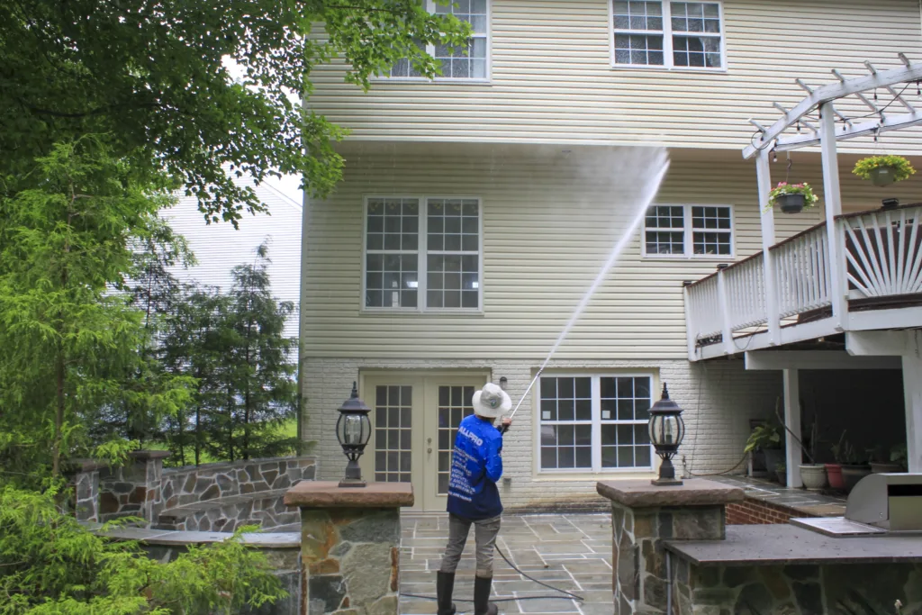AllPro technician washing the back of a three-story home with a raised deck