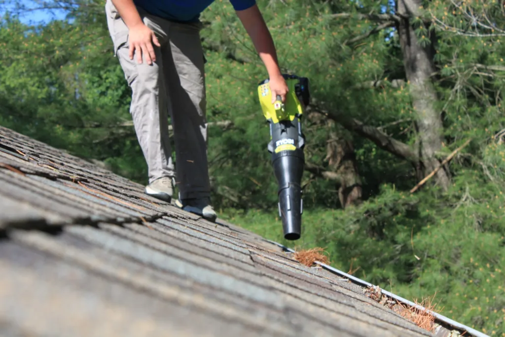 AllPro technician on a roof clearing gutters with a leaf blower