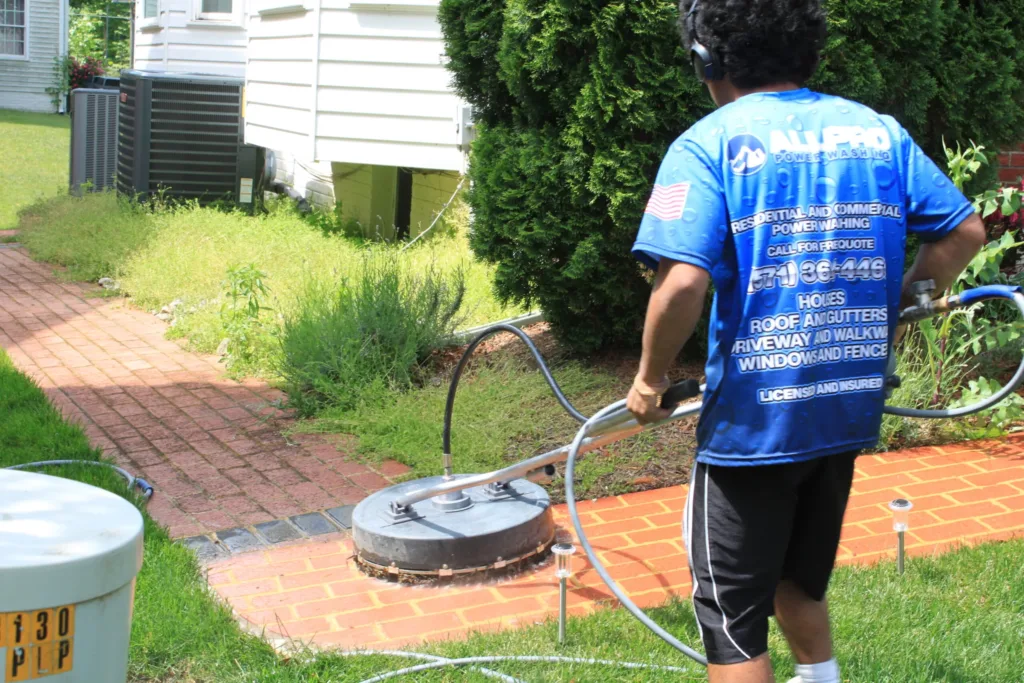 AllPro technician cleaning a brick paver walkway with a surface cleaner
